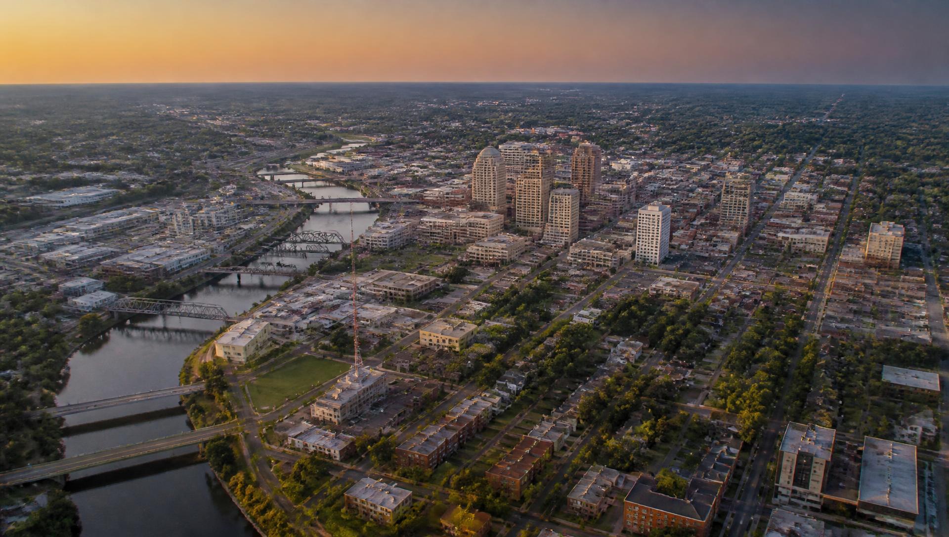 Aerial view of a city at golden hour showing streets, rooftops, bridges and neighborhoods